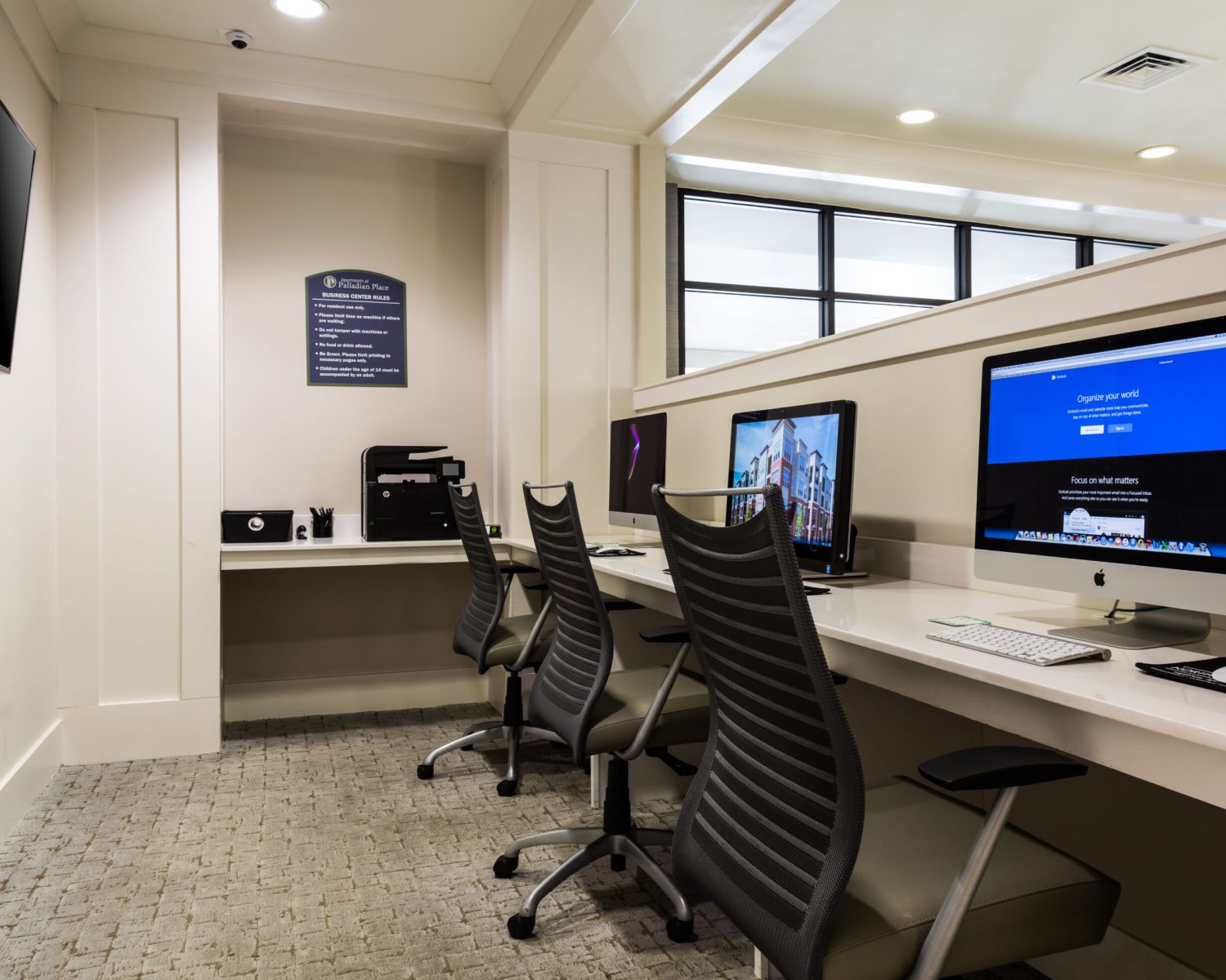 Apartments at Palladian Place with a business center, a desk, computer monitor, desk lamp, and comfy office chair